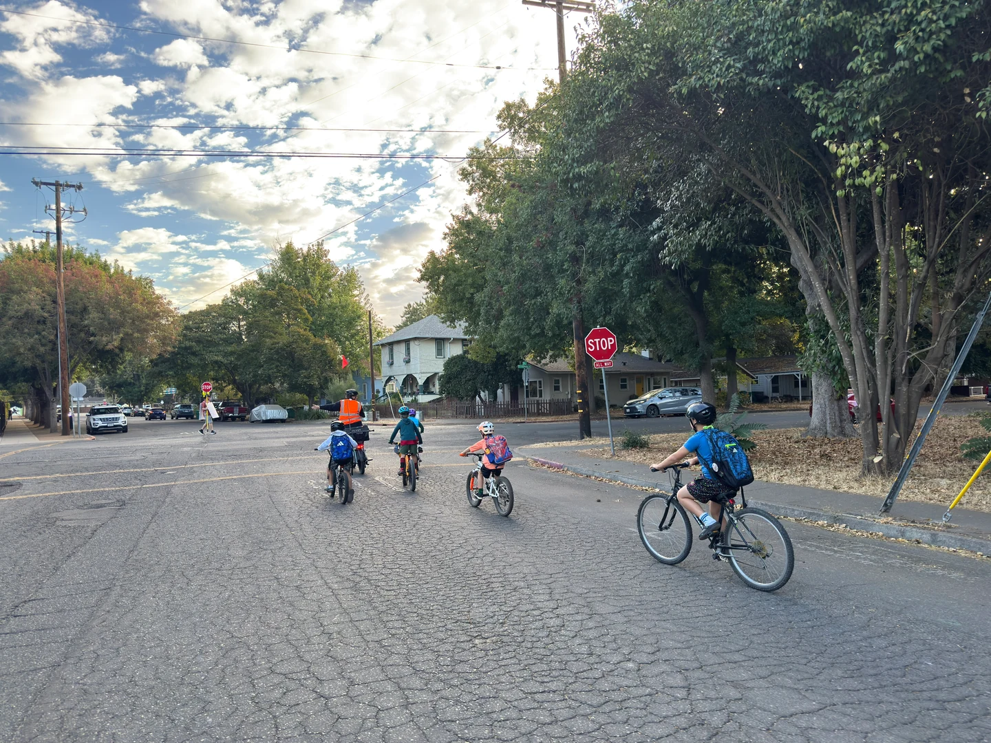 Cyclists approaching a neighborhood intersection with a stop sign