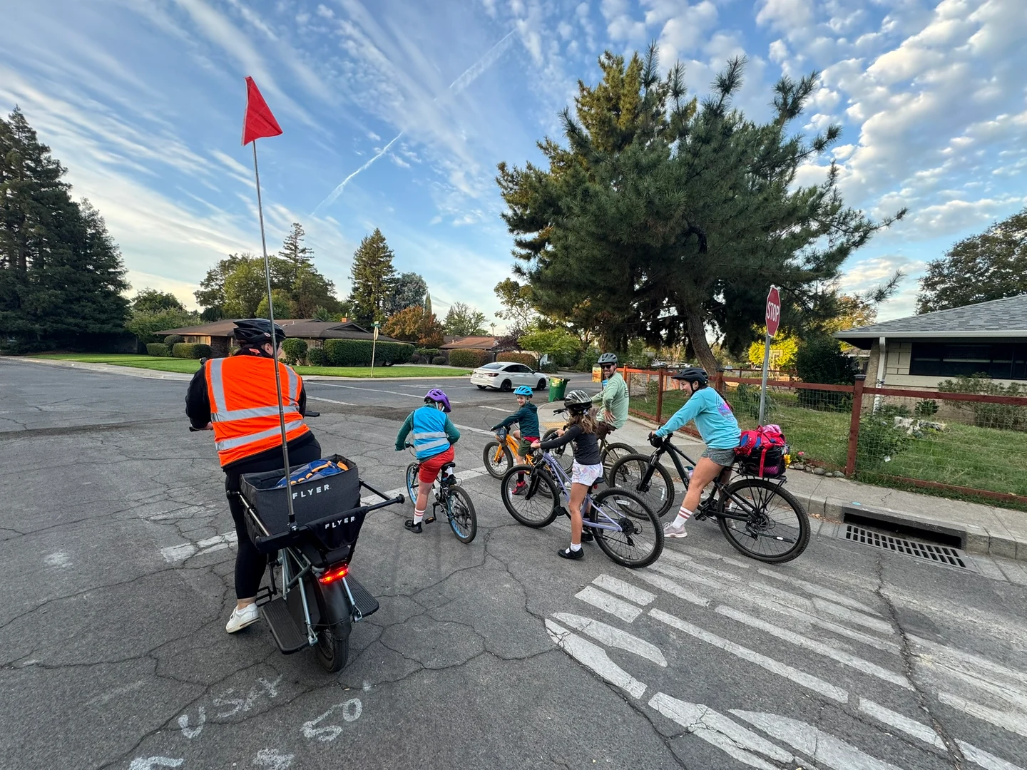 The riding group gathered at a crosswalk beneath a red safety flag